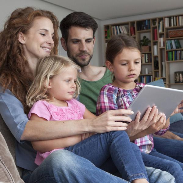 Eine Familie schaut auf ihr Tablet.