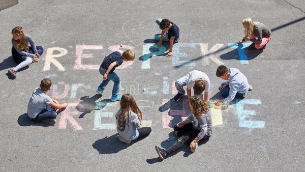 Kinder malen mit Kreide den Schriftzug "Respekt für meine Rechte"