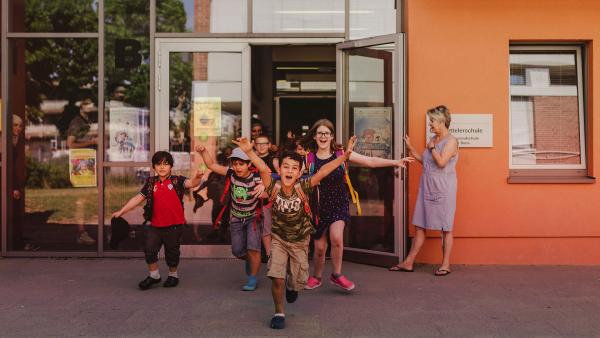 Die Kinder freuen sich auf die Pausenzeit und stürmen aus dem Schulgebäude.