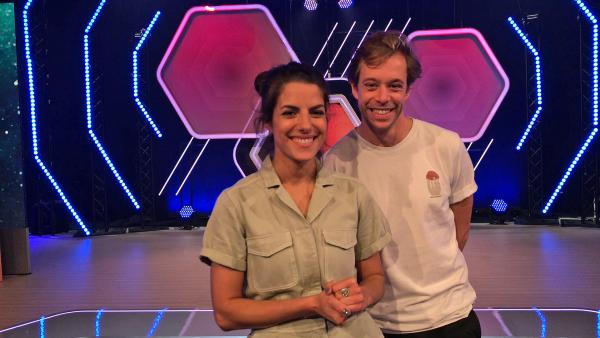 Clarissa Corrêa da Silva und Tobias Krell stehen in einem Studio und lächeln in die Kamera.