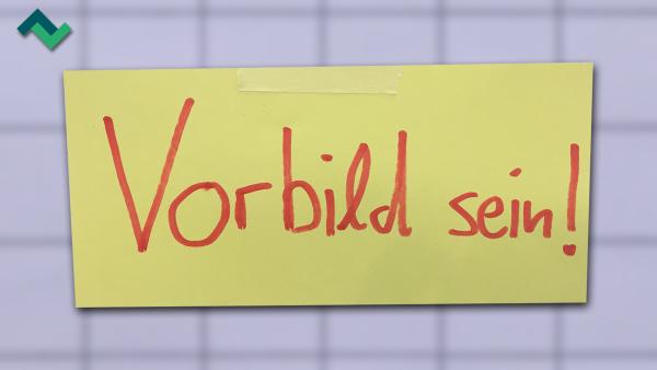 Ein gelber Notizzettel, auf dem "Vorbild sein" geschrieben ist.