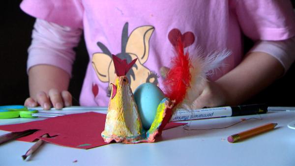Kind malt einen Eierkarton-Huhn mit Pinsel und Farbe an. 