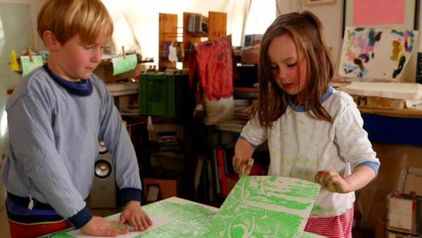 Zwei Kinder experimentieren mit Kleister und Farbe.