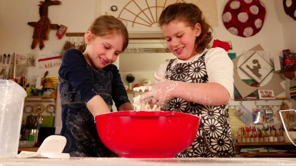 Zwei Kinder experimentieren mit Maisstärke und Wasser.