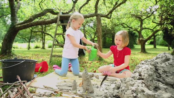 Zwei Mädchen experimentieren im Garten mit Lehm