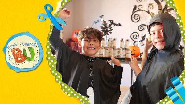 Zwei Jungs Halloweenkostüm vor einem gebastelteten Klorollen Mumienspiel. 