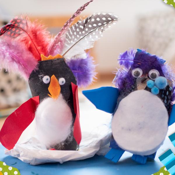 Zwei Pinguine aus Klopapierrollen geschmückt mit Federn, Papier, Watte und Pompons.