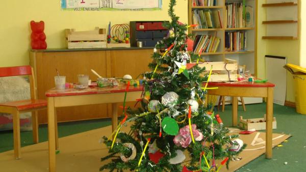 Ein Tannenbaum in einer Kindertagesstätte. Er ist mit bunten Sternen, Korken und Papier geschmückt.