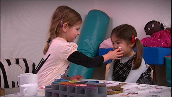 Emma und Sofia schminken sich mit bunter Farbe.