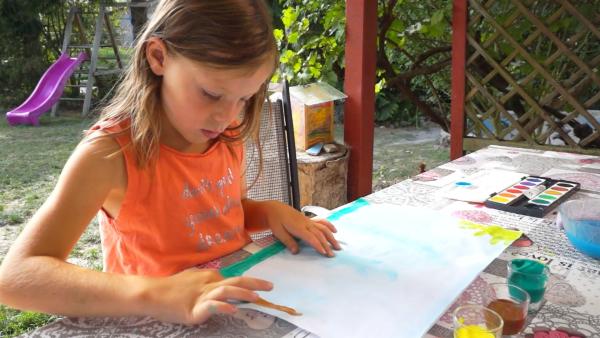 Leonie malt mit brauner Farbe.