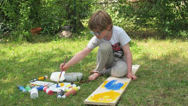 Liam malt auf Holz.