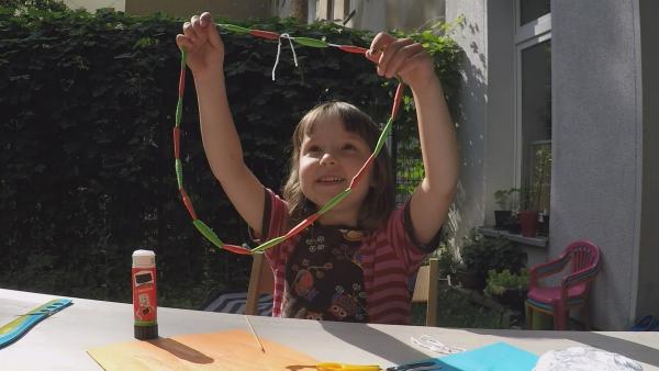 Anna bastelt eine Kette aus Papier.