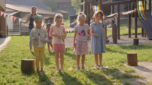 Vier Grundschulkinder stehen auf einer Wiese. Sie halten je einen Löffel mit einem Ei in den Händen.