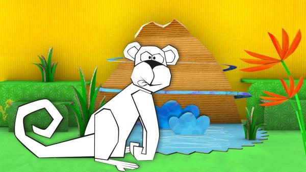 Der gebastelte Affe aus Papier von ENE MENE BU sitzt am Wasser.