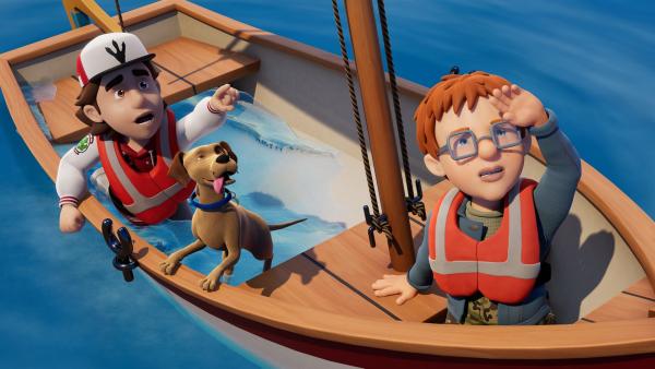 Norman steht am Bug eines Segelbootes, das voller Wasser ist. Peter sitzt mit einem Hund an der Seite. Alle schauen auf etwas schräg über ihnen. Peter zeigt mit erhobenem Arm darauf.