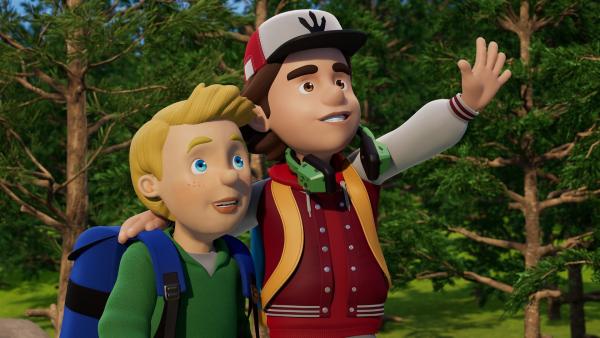 James und Peter stehen zusammen im Wald. Peter hat seinen Arm um James' Schulter gelegt. Mit der anderen Hand winkt er.