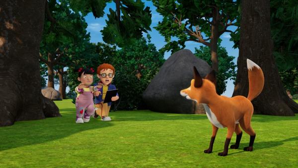 Das kleine Mädchen Lily läuft mit ausgestreckten Händen zu einem Fuchs, der auf einer Lichtung im Wald steht. Norman hockt mit einem Zeichenblock auf dem Knie neben Lily und schaut besorgt zu ihr.