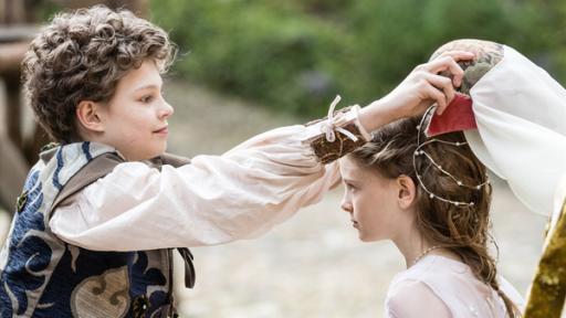 Rechte: KiKA/Česká televize/Petr Čepela Links steht Leopold seitlich. Mit ausgestreckten Arme hält er einen Haarschmuck mit Schleier über Josefinas Kopf. Josefina schaut zu ihm.