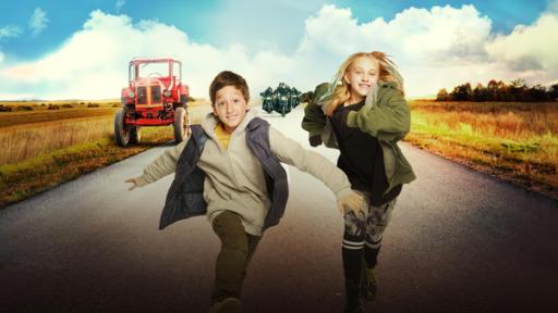 Junge und Mädchen rennen gemeinsam. Im Hintergrund ein Traktor.