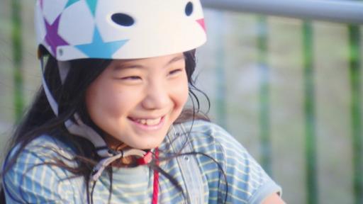 Rechte: SR/NHK Fumis lächelnd und sehr nah. Sie trägt einen Fahrradhelm auf dem Kopf. Im Hintergrund ein Geländer.