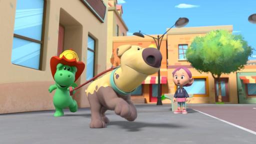 Dinki muss zum Jupilola | Rechte: © 2023 MONDO TV Group, Pagot, Calidra, T2T, ZDFS Grisu, der kleine grüne Drache mit dem roten Feuerwehrhelm, hat den Hund Dinki an der Leine. Beide rennen sie durch eine Straße von Drachenstadt. Etwas abseits beobachtet sie dabei Stella.