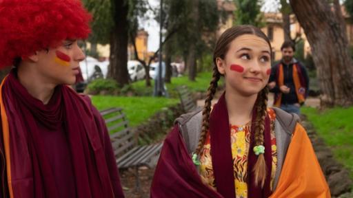 Home Sweet Rome! - „Calcio“ ist italienisch für Fußball (S01/E08) | Rechte: Red Monk Studio/hr Lucy und Nico tragen Schals und Perücken in den Farben ihrer Fußballmannschaft – orange und rot.