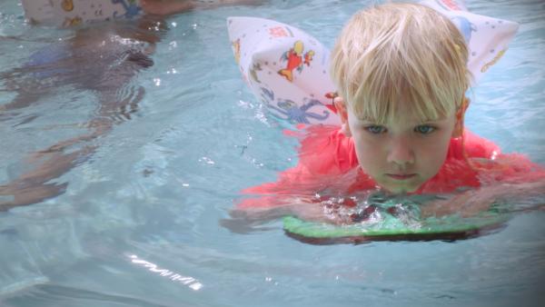 Eddie schwimmt mit einer Schwimmhilfe im Wasser.