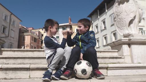 Die Freunde Elmin und Erik sitzen zusammen auf einer Treppe in der Stadt. Sie haben einen Fußball dabei, denn sie lieben Fußball.