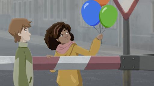 Jenseits der Mauer | Rechte: © 2024 Mideu Films, ZDF, Beside Production Durch eine heruntergelassene Schranke getrennt, stehen sich Paul und Millie gegenüber. Millie hält drei farbige Ballon in einer Hand. Beide blicken sehnsüchtig auf die Ballons. Im Hintergrund ist eine graue Straßenschlucht zu sehen.