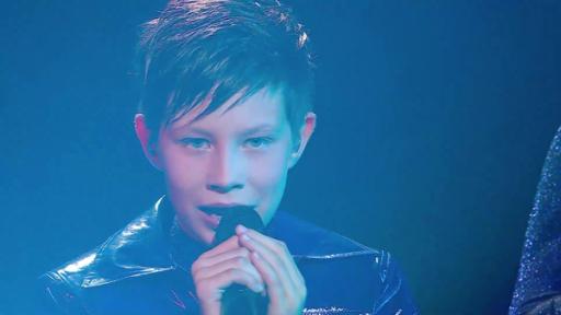 Artem Kotenko singt in ein Mikrofon, um ihn herum blaues Licht
