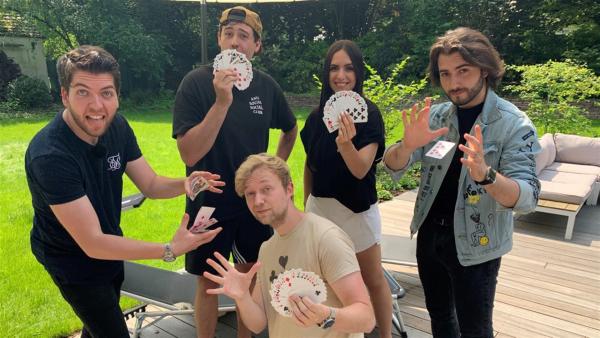 Jess trifft mit den Zauberern Alexander Straub, Marc Weide, Sos Jr. und CrispyRob auf geballte Magie. Sie halten alle Spielkarten in den Händen und zeigen diese offen. 