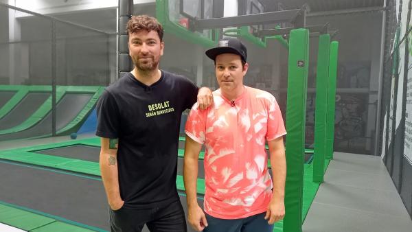 Ben steht rechts neben Marteria. Im Hintergrund sind Trampoline einer Trampolinhalle.