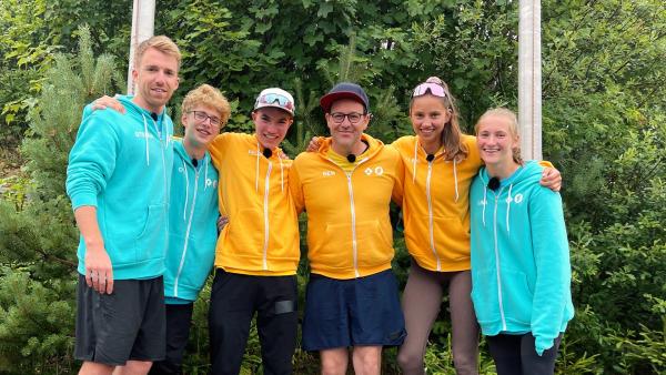 Das Team „KiKA LIVE“  und das Team "Die Sportmacher" posieren in einer Reihe für ein Foto. Felix, Ben und Alena sind in der Mitte des Fotos zu sehen. Die anderen stehen links und rechts von ihnen. 