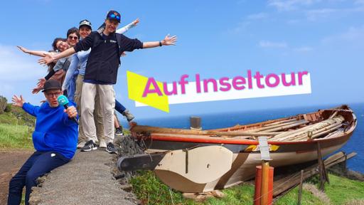 Ben begleitet die Schülerinnen und Schüler bei Ausflügen. Sie stehen auf einer Mauer und posieren mit gestreckten Armen. Daneben steht ein Boot. Im Hintergrund ist das Meer zu sehen.