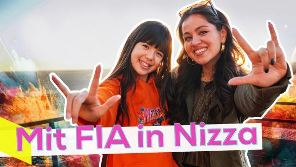 FIA links und Sarah rechts eng beieinander vor einem Geländer. Beide lächeln. Hinter ihnen bunte Wellen, die sich brechen. In der Ferne das Meer. Unten die Aufschrift: Mit FIA in Nizza.