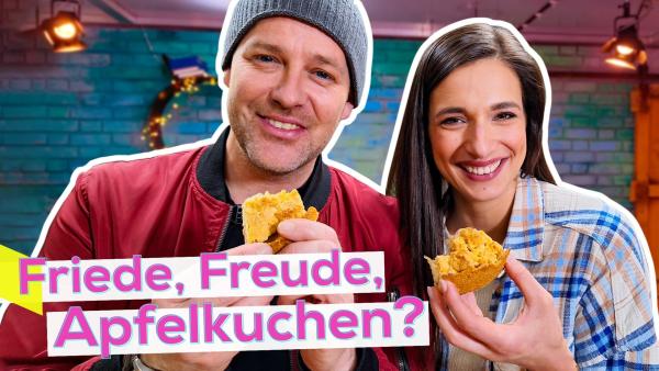 Ben und Sally eng nebeneinander. Beide halten je ein Stück Kuchen vor sich in der Hand und lächeln. Unten die Aufschrift Friede, Freude, Apfelkuchen?