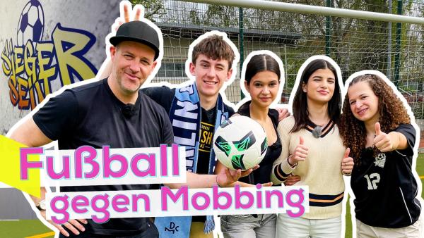 Links hält Ben einen Fußball in der Hand. Dicht neben ihm der Cast aus dem Film eng nebeneinander. Im Hintergrund ein Fußballplatz mit Tor und ein Teil des Filmplakats. Unten links die Aufschrift Fußball gegen Mobbing.