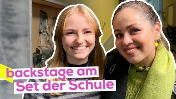 Links Darstellerin Jamila und Sarah rechts eng nebeneinander. Beide lächeln. Im Hintergrund ein Flur der Schule. Aufschrift unten links: backstage am Set der Schule.