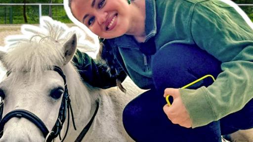 Rechts hockt Sarah neben einem liegenden Shetlandpony. Sie lächelt. Im Hintergrund ein Reitplatz mit Sandboden und Büschen dahinter. Aufschrift links: super süße Ponys.