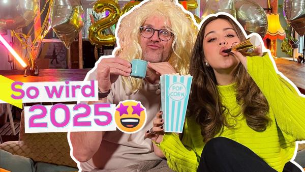 Ben und Sarah sitzen eng nebeneinander auf einem Sofa. Ben trägt eine blonde Perücke und Sarah hält einen Popcorn-Becher in der Hand und pustet in eine Tröte. Im Hintergrund bunte Lichter und Folienballons. Aufschrift: So wird 2025.
