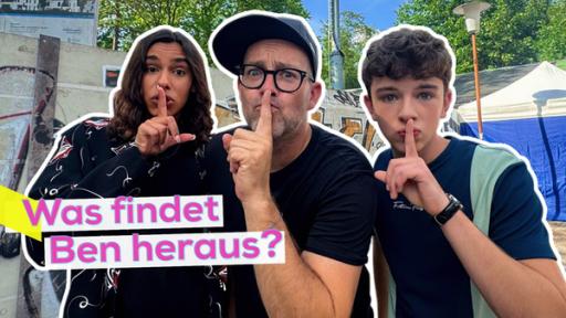 Rechte: KiKA/Andrea Thoben Ben zwischen den Schloss Einstein Darstellern Dean-Ryan Kuhlig und Marlon Heinrich. Sie stehen eng nebeneinander und halten sich mit einer Pssst-Geste die ausgestreckten Zeigefinger vor den Mund. Aufschrift: Was findet Ben heraus?