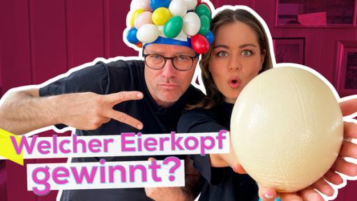 Sarah und Ben treten gegeneinander an im Eier-Battle | Rechte: KiKA / Torben Hagenau Links Ben mit einer Badekappe an der viele Eier aus Plastik kleben. Rechts dicht neben ihm Sarah mit erstauntem Gesichtsausdruck. Sie hält ein Straußen-Ei in die Kamera. Aufschrift: Welcher Eierkopf gewinnt?