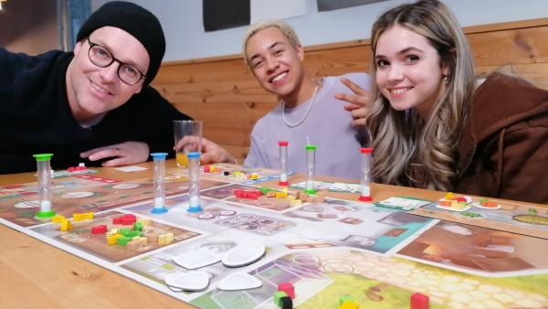 Ben spielt mit Noel Okwanga und Josie Hermer aus Schloss Einstein verschiedene Brettspiele.