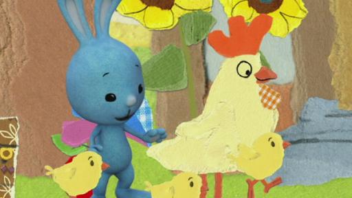 Kikaninchen mit einem Huhn und drei Küken vor zwei Sonnenblumen