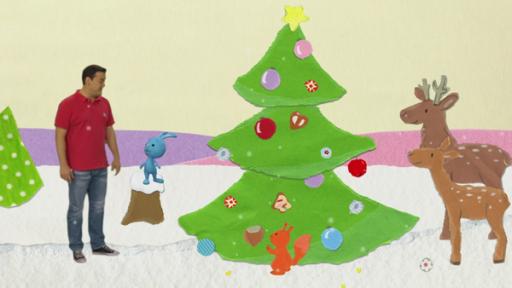 Kikaninchen, Christian und zwei Rehe stehen auf einer verschneiten Lichtung vor einem geschmückten Tannenbaum.
