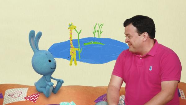 KiKANiNCHEN und Christian beobachten eine Giraffe am See.