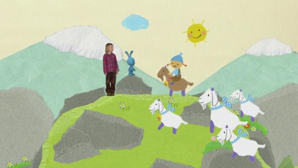 Kikaninchen mit einem Kind, der Bergmarie und Ziegen auf einem Berg