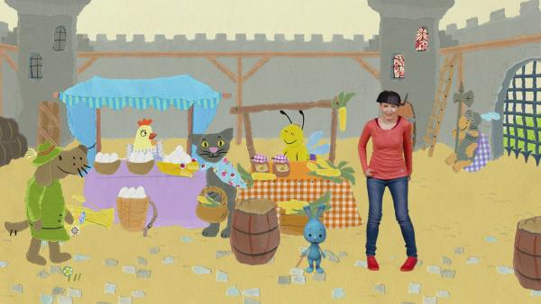 Anni und Kikaninchen mit vielen Tieren auf einem Markt vor der Burg