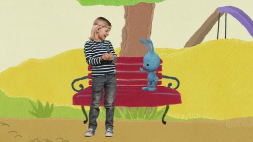 Kikaninchen und Luis auf einer roten Bank unter einem Baum.