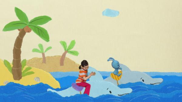 Kikaninchen und Ronja reiten auf Delfinen über die Wellen des Meeres.